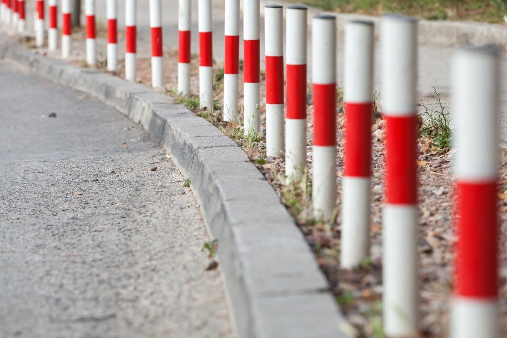 Striped red and white signal poles stand on border of asphalt roadside