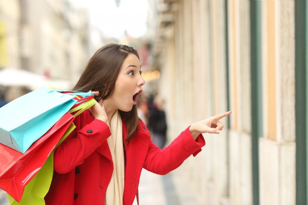 Amazed shopper opening mouth holding shopping bags