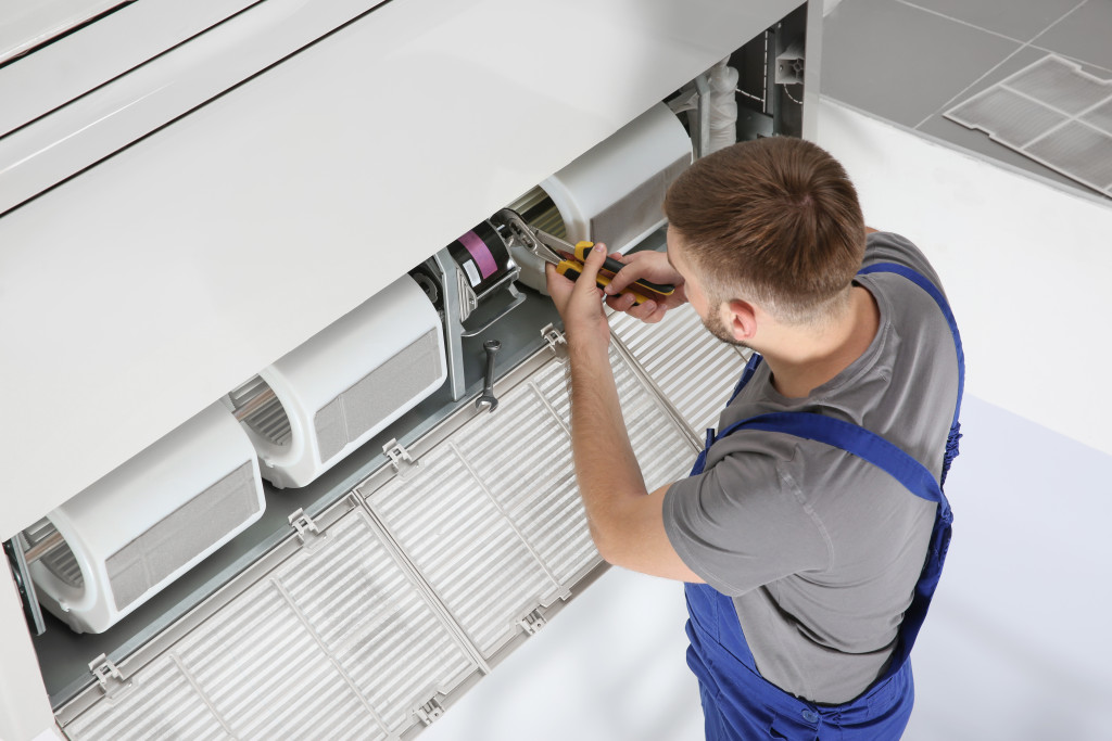 male technician repairing air conditioner indoors