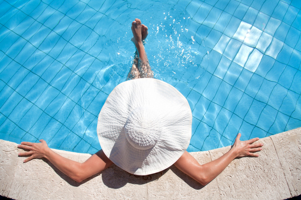 woman in big hat relaxing on the swimming pool